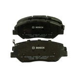 Top-down view of two pads showing painted back plates with printed Bosch logo, part number 0 986 AB3 081-KTG, batch code 17701 25X BNA140 and 'MADE IN TAIWAN' text; one pad has a spring-steel wear indicator clip at the upper edge