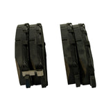 Edge-on view of two pads stacked, showing friction material thickness and the bent stainless-steel anti-rattle/wear indicator spring protruding from the left pad