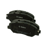 Angled view of both pads stacked with Bosch logo and moulded part numbers clearly legible on the backing plate, showing the asymmetric outline typical of a Hyundai/Kia front pad
