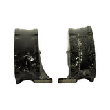 Edge-on view of two pads back-to-back showing tab-ear backing plate profile, curved friction surface with stepped chamfer, and the shrink-wrap tightly conforming to the part