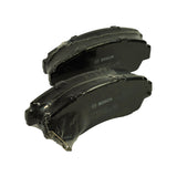 Angled view of both pads with the pair of looped wire anti-rattle springs partially installed between them, mounting-ear geometry visible