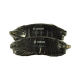 Two pads laid back-to-back showing stamped identifiers on steel backing plates: 'BOSCH', '0 986 AB3 144', '17304', 'E86', 'BNA138' — and shaped ear/tab profile with anti-rattle clips
