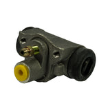 Three-quarter angle showing brake line inlet thread with brass fitting, two threaded mounting holes on the flat mounting face, yellow plastic dust plug in one end bore and rubber dust boot on the other