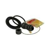 Kit components arranged showing dust boot and spring wire in foreground. Boot has prominent ribbed accordion profile with flared base and narrower top. Two separate grease pouches visible — amber/yellow and red-orange — partially separated from shared sachet packaging. Small cylindrical rubber cap/bleeder-valve dust cover also visible at left.