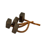 Brushes lying on side showing profile, copper leads extending in different directions. Rectangular cross-section of carbon blocks clearly visible. Minor surface oxidation on lead braid ends consistent with storage age.