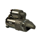 Three-quarter rear-left view of starter motor. PASSED / Remy Korea QC label prominent on field housing. Drive lever return spring and pivot bracket visible at solenoid base. Nose cone with internal drive pinion visible at far end.