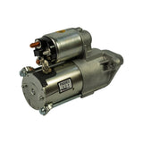 Three-quarter front-left view showing commutator end cap with four through-bolt heads and brush holder plate. PASSED / Remy Korea QC label on field housing. Solenoid with copper stud terminal at top, control terminal below. Yellow QC dot on solenoid cap.