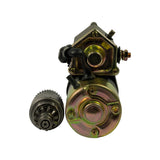 Rear and commutator-end view of starter body with drive assembly placed beside it; yellow sticker on solenoid housing partially visible reading '24V'. Drive assembly shows 9-tooth pinion and reduction gear cluster.