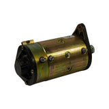 Three-quarter rear-left view. Terminal labels D+ visible on rear bracket. Band-clamp construction and field terminal posts visible on body. Minor oil/dust residue on lower body surfaces.