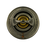 Top-down view of thermostat showing the circular flange face, central wax pellet dome with brass centre, cross-brace valve frame, and small copper jiggle pin at the lower edge. Faint stamping visible around the inner ring, reads partially as '8266' consistent with the part number.