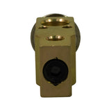 End-on view of the refrigerant inlet/outlet face showing two large concentric port bores (high-side and low-side passages) plus a small equaliser port, all machined into the brass block body. Schrader-type valve core visible in the lower port.