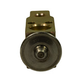 Direct end-on view of the thermostatic power element capsule (stainless steel disc with central actuator pin). Mounting tab and inlet/outlet bores partially visible behind. Surface shows minor oxidation tarnish consistent with storage age.