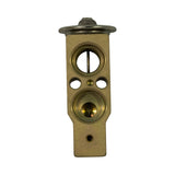 Flat-face view (block mating face) showing two large circular refrigerant ports with internal cross-pin orifice detail, two oval mounting bolt clearance slots, one small equaliser port, and a small bleed/pilot hole at base. This is the evaporator-side mating face.