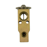 Opposite flat-face view (condenser-side mating face) showing the larger suction port with internal cross-pin and the smaller liquid port with Schrader core, plus two mounting slots and equaliser port. Minor surface oxidation on brass body.