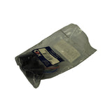 Angled side view of the sealed bag showing the OEX label partially folded, contents settled to one side exposing a black moulded plastic connector body and coloured wire loom.