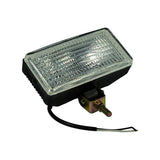 Three-quarter front-angle view of the work lamp out of box; rectangular black housing with clear fresnel-patterned glass lens, single-bolt swivel bracket visible at centre-bottom, two bare lead wires (black and white) exiting cable grommet on left side