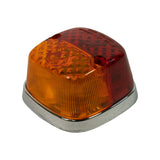 Three-quarter angled view showing lamp profile depth and chrome base surround. Moulded text on red lens upper edge partially visible. Amber section occupies upper portion, red lower. Chrome rim in good condition.