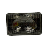 Front lens face of the sealed beam lamp, straight-on view. Clear ribbed glass lens with typical Type 1A1 rectangular pattern. Koito brand oval badge partially visible through lens on reflector rear housing, confirming Japanese manufacture. Box label visible in reflection.