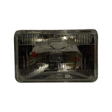 Full-face front view of lens, rectangular with moulded prismatic optic pattern; small raised STANLEY nameplate badge visible at centre of reflector behind lens; four mounting tabs at corners.