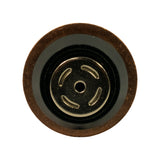 End-on view of the rear nickel-plated cap, showing four evenly spaced curved relief slots around a central locating hole, surrounded by a black rubber sealing ring inside the copper outer rim