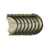 Top-down view of stacked bearing shells still sealed in clear plastic sleeve, crescent profiles aligned, plain running surfaces showing light shelf discolouration
