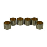 Six bushings lined up on end showing the vertical split seam down the side of each shell, bronze bore facing camera