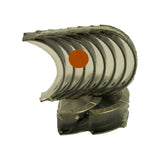 Upper stack of plain half-shell main bearings sitting on top of the thrust-flanged pair, still in their clear shrink-wrap with orange size-grade dot applied to the middle shell