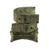 Side view of three stacked shrink-wrapped bearing shell pairs. Top and middle stacks are plain journal bearings with locating tangs and oil holes; bottom is the flanged thrust bearing with integral thrust faces. Faint stamped markings visible on shell edges
