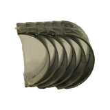 Side profile of the shrinkwrapped bundle showing six stacked half-shell bearings nested together, bright tinned running surfaces facing the camera