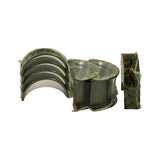 Three stacked half-shell bearings still in sealed plastic showing the bright silver running surface and Babbitt overlay; light yellow tarnish spots visible on the bearing backs
