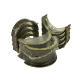 Close-up of the flanged thrust bearing (centre main) in sealed plastic with the characteristic thrust flanges on both sides; adjacent stack shows the half-round profile of the standard main shells