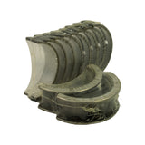 Fanned view of all ten bearing shells in shrink wrap — five upper halves and five lower halves — with the flanged centre main shell displayed prominently in the foreground