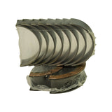 Stack of ten half-shell bearings fanned out showing the plain-backed outer surface, with the flanged thrust pair visible at the base