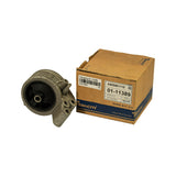 Part removed from box and placed beside it; circular rubber isolator face visible, die-cast alloy housing with offset three-bolt flange bracket to the right. Box label confirms AWSMI1115 / 01-11389 / EXPO 2.4 / MITSUBISHI. Part appears uninstalled, no bolt impressions.