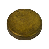 Three-quarter angled top view of a single brass cup-type Welsh plug showing domed convex face with aged patina and minor surface oxidation