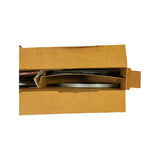 Close-up open-box view from opposite end showing bright chrome-finish oil control ring rails stacked on right side and dark compression rings with paper sleeve on left. Chrome surface appears pristine.