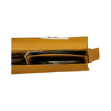 Opposite-end top-down view into box showing flat dark compression rings and thin oil rail rings stacked on the right side of the divider, with the wavy expanders visible on the left edge. A white label/instruction slip is partially visible under the box flap.