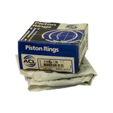 Three-quarter angle of closed ACL Piston Rings box on top of the folded instruction wrapper, confirming part number C1805-1.00 and TO SUIT TOYOTA 4AF on front label; box shows moderate shelf wear with creasing and scuffing to corners.