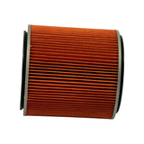 Low-angle side profile of the filter element lying on its side, showing full height of the pleated orange paper element and both metal end caps with black rubber sealing rings.