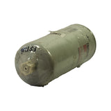 Three-quarter angle showing base end of filter. White plastic drain port hex fitting visible at dome cap. 'FS1216' handwritten in marker on dome. Barcode sticker visible on top. Wrap is creased and dusty but intact.