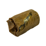 Three-quarter view of bearing set in torn wrapper. Bearing shells visible through tear — bimetal construction evident with brass-coloured bearing surface and darker steel backing. Small text stamped on shell face visible but not fully legible.