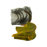 Close-up of bearing set contents: stacked half-shell journal bearings (4 or 5 pieces) wrapped in clear poly, copper-backed steel visible on outer face; flanged thrust bearing (No. 5 position) wrapped in yellow/green poly film below. Both packages intact but unsealed or loose from age.