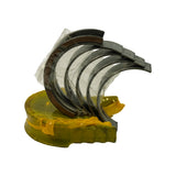 Opposite-quarter fan-out view of bearing shells. Protective clear plastic film still on most shells. Stamped size markings faintly visible on outer edge of upper shells. Yellow tray base.