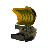 Angled overhead view showing both upper half-shells (still on yellow tray) and lower half-shells laid out below. Steel-backed outer surface clearly visible on lower shells; tri-metal layers discernible at edges.