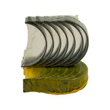 Front-on view of bearing set stack showing upper shells (silver face, dark back) seated atop lower shells (yellow coating), both groups still in clear protective wrap. Bearing arc shape and flanged edges visible.