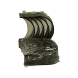 Fan of 5 upper bearing shells in plastic wrapping, standing upright. Dark bimetal bearing surface visible on inner face; oil groove channel clearly present. Tabs and locating tangs visible at split line.