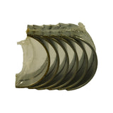 Set of six bearing half-shells fanned out, inner face (bearing surface) visible — smooth white-metal overlay on steel-backed half-shells, original clear protective wrapping still partially intact around the bundle.