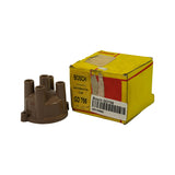 Part removed from box and placed alongside original yellow Bosch box. Box face reads 'BOSCH PACKED DISTRIBUTOR CAP GD 706' in large print, with handwritten '4 cylinder' below part number. Retailer barcode label affixed to front reading 'Bosch GD706 / IGN-00662'. Box shows significant shelf wear and torn label area.