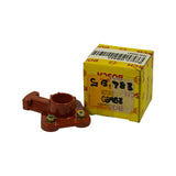 Part alongside closed box; box in background shows label and part number GB983. Part positioned to show top face and shaft socket. Three brass contact screws visible on body surface.