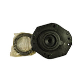 Angled view of the underside of the strut mount, central piston bore in focus, with green paint dots on flange visible (Monroe QC marks). Bagged bearing component beside it.